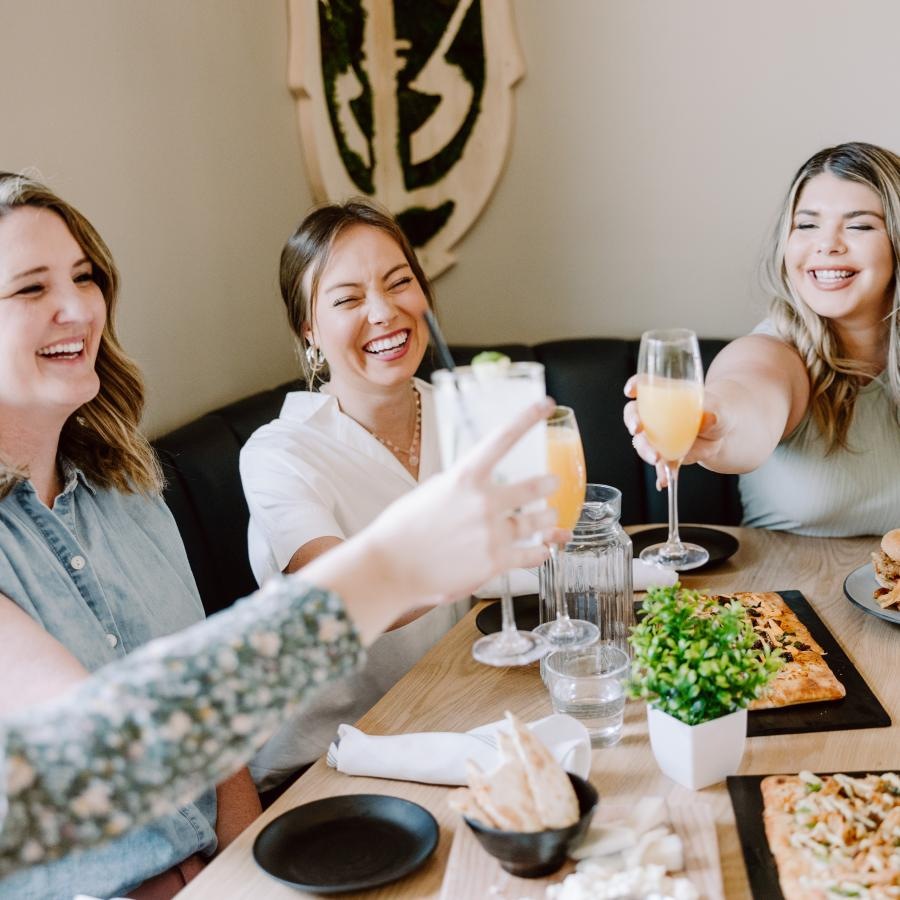a group of women sitting at a table with food and drinks