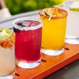 a group of glasses with different colored drinks in them